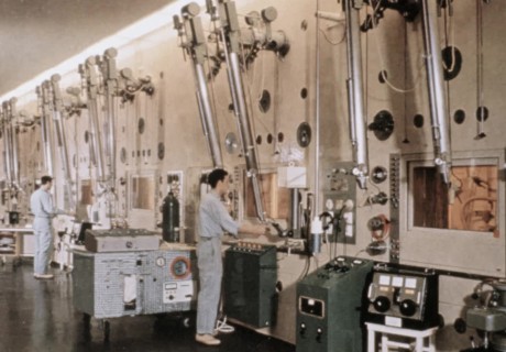 Ausschnitt aus einem alten Film, in dem Arbeiter vor riesigen Apparaten stehen