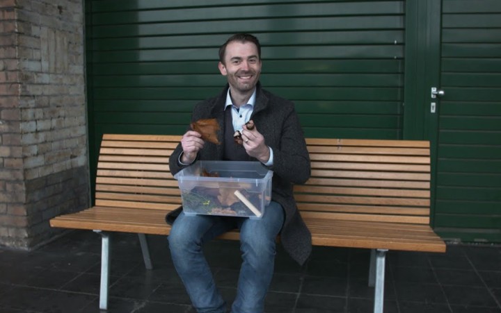 Ein mann sitzt draußen auf einer Bank und hat eine Kiste auf seinem Schoss