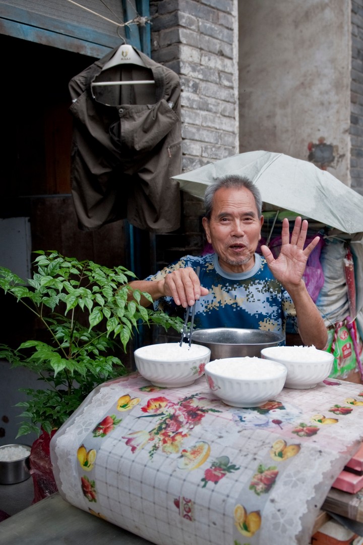 Ein Mann sitzt am Tisch vor ein paar Schalen mit Reis