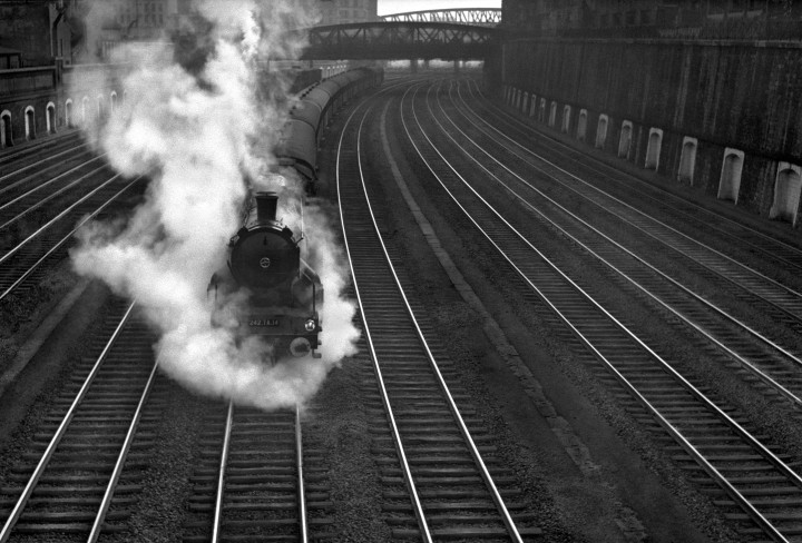 sch/w Foto von René Groebli. Dampfende Lok fährt auf Schienen dem Betrachter entgegen.