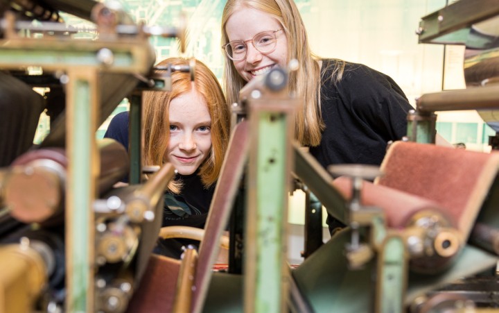 Zwei Mädchen betrachten eine Maschine aus der Nähe