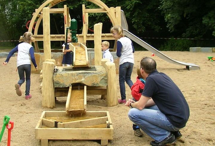 Spielplatz mit spielenden Kindern und ihren Eltern.