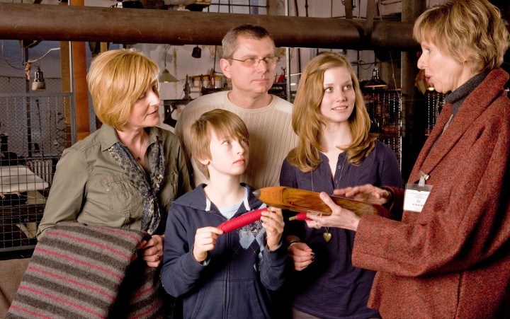 Family look at a large spindle with a museum guest guide
