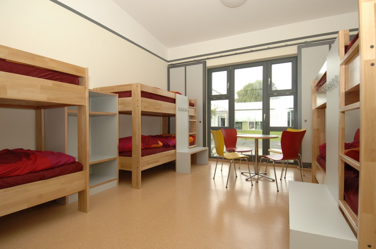Glance into a bedroom with three bunk beds and a table and chairs
