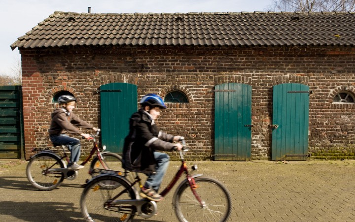 Zwei Jungen radeln schnell mit Fahrrädern an historischem Gebäude vorbei