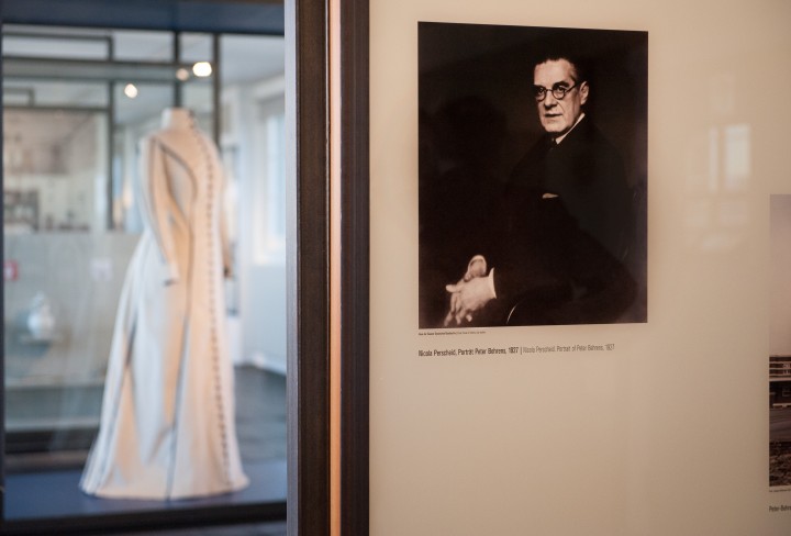 Blick in eine Ausstellung mit einem Portrait eines Mannes an einer Wand und einem Kleid an einer Figurine