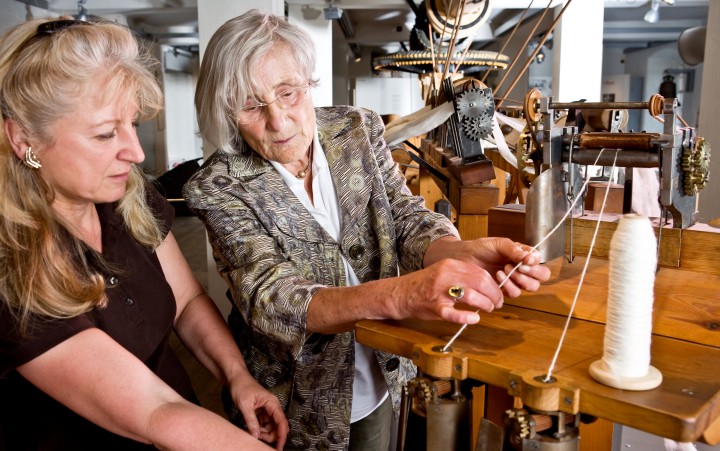 Two ladies explore the historic spinning machine